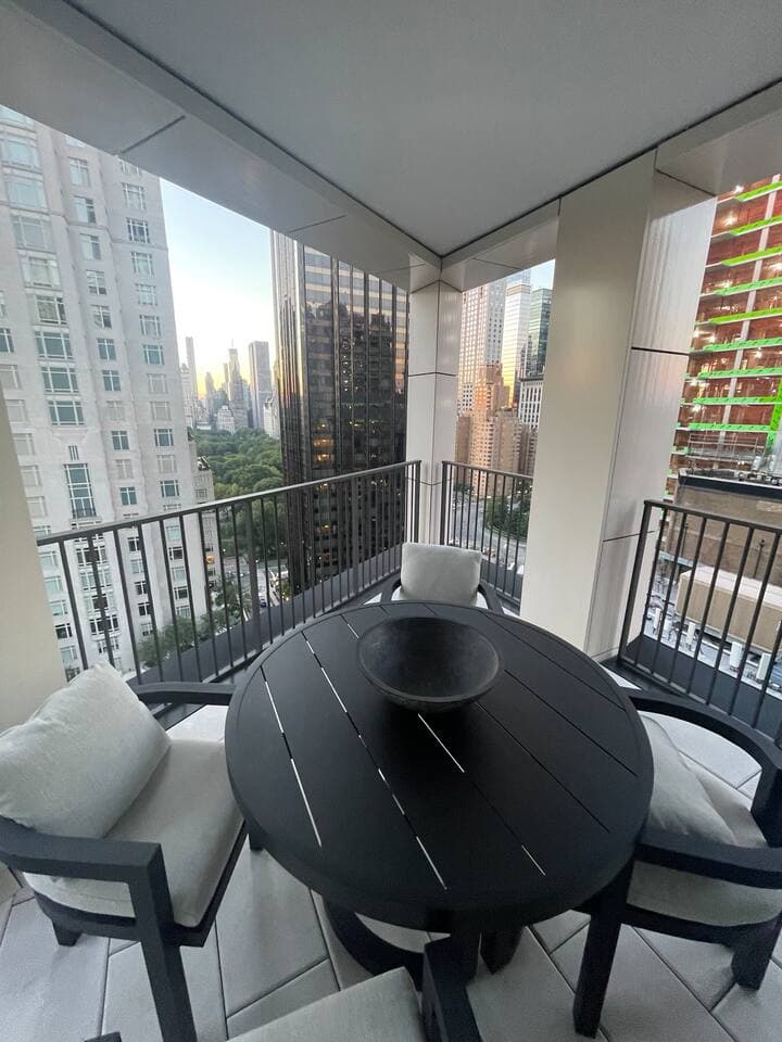 Outdoor balcony with table and chairs facing views of Central Park and Columbus Circle.